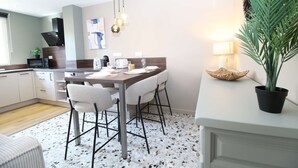 A modern kitchen with a dining area, including a table set for four, a coffee machine, and a microwave. - ⭐Au calme des Carmes⭐Climatisation⭐Wifi⭐Hypercentre (Avignon)