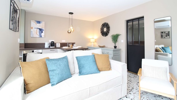 A modern living room with a white sofa, a coffee table, and a dining area with a kitchen in the background. - ⭐Au calme des Carmes⭐Climatisation⭐Wifi⭐Hypercentre (Avignon)