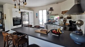 A modern kitchen with a central island, built-in oven, and a large window. - Village house with garden. Pets allowed (La Flotte)
