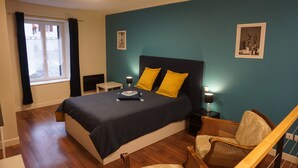 A bedroom with a large bed, a nightstand, a chair, and a window with curtains.