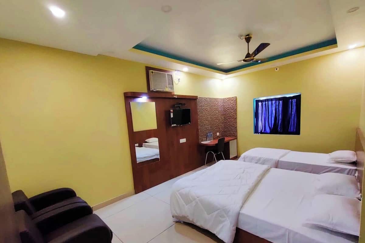 A hotel room with two beds, a desk, a chair, a ceiling fan, and a window with curtains.