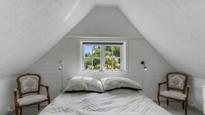 A bedroom with a sloped ceiling, a window, two chairs, and a bed with striped bedding. - "Ilze" - 20m from the sea by Interhome (Bandholm)