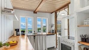 A modern kitchen with wooden beams, large windows, and a view of the outdoors. - "Ilze" - 20m from the sea by Interhome (Bandholm)