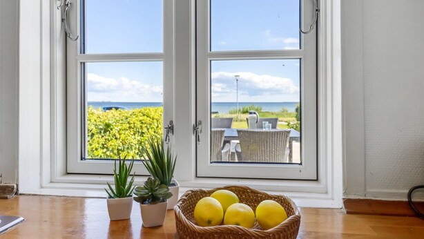 A room with two windows overlooking a garden and a view of the sea. There is a wicker basket with lemons on the floor. - "Ilze" - 20m from the sea by Interhome (Bandholm)