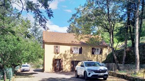 A house with a gravel driveway, a parked car, and a stone wall. - Renovated apartment in quiet country house with view of the Cevennes mountains (Portes)