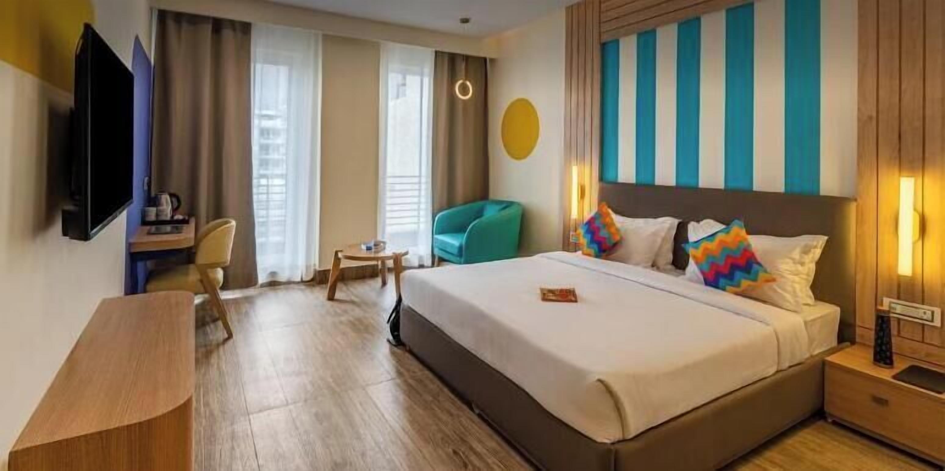 Una habitación de hotel con una cama, un escritorio, una silla y un televisor.