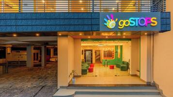 A building entrance with a 'goSTOPS' sign, a staircase leading up, and a glass door entrance.