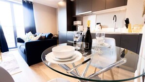 Una cocina moderna con armarios oscuros, una mesa de comedor de vidrio y un sofá en la sala.