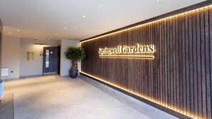 Una zona de recepción con un panel de madera, una planta en maceta y un cartel que dice 'Springwell Gardens'.