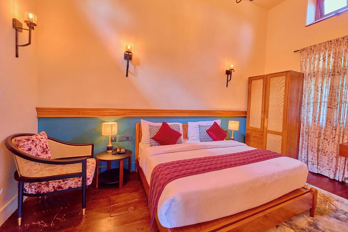 Quarto com cama, uma cadeira, mesa de cabeceira e guarda-roupa.