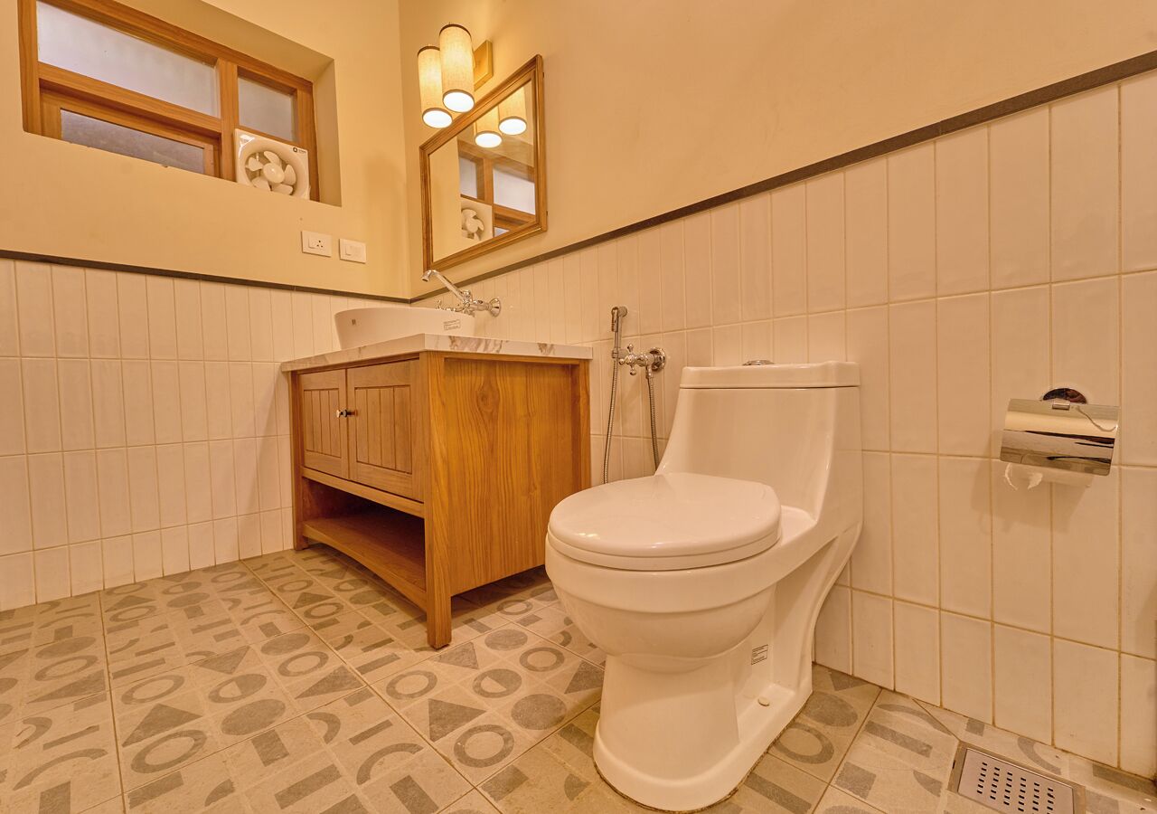 Ein Badezimmer mit einer weißen Toilette, einem Holzkosmetikschrank und einem Spiegel mit Beleuchtung darüber.