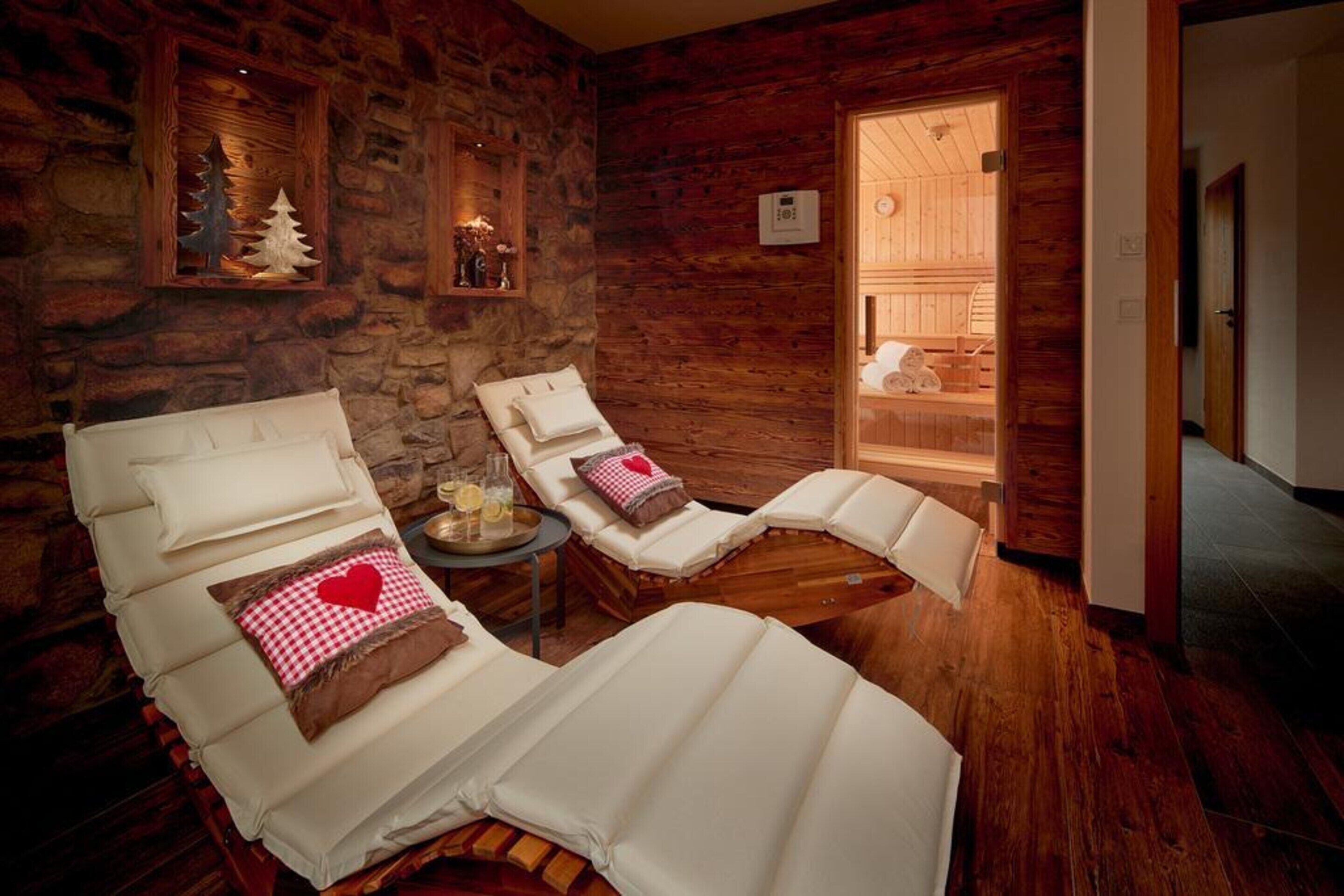 Ein Spa-Raum mit zwei Liegestühlen, einer Steinwand und einer Holztür, die in einen anderen Raum führt.