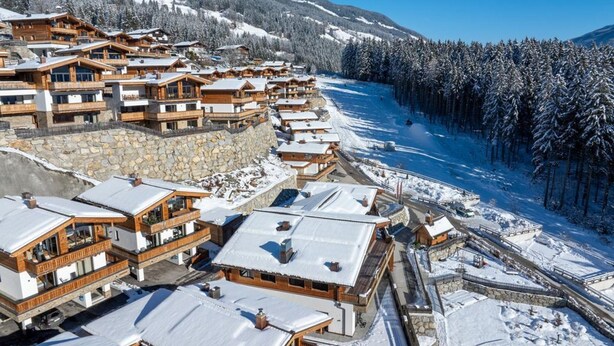 A snow-covered resort with wooden buildings and a ski slope. - Chalet Near Ski Lift With Garden (Neukirchen am Grossvenediger)