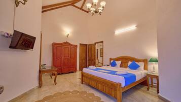 A bedroom with a wooden bed, a red wardrobe, a small table, and a chandelier.