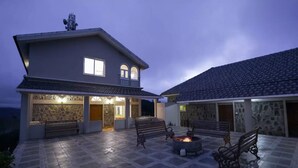 Ein zweistöckiges Haus mit Naturstein-Fassade, einem Feuerkorb und Sitzgelegenheiten im Freien.