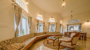 Ein geräumiges Wohnzimmer mit einem großen Ecksofa, einem Couchtisch und einem Essbereich mit Holzmöbeln.