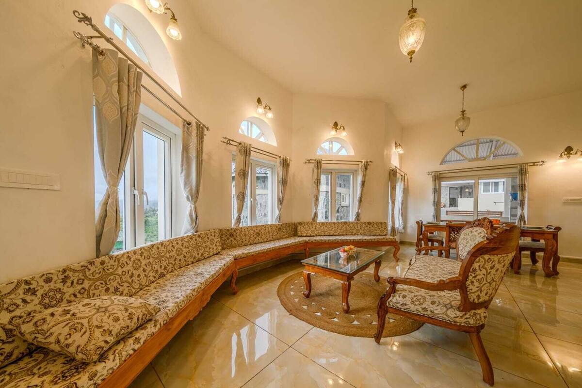 Amplia sala de estar con un sofá modular grande, una mesa de centro y un comedor con muebles de madera.