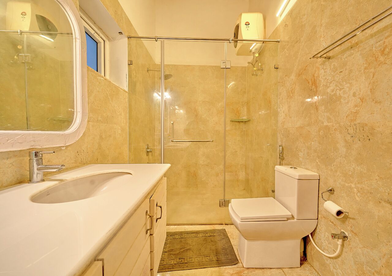 A bathroom with a glass-enclosed shower, a toilet, and a sink.