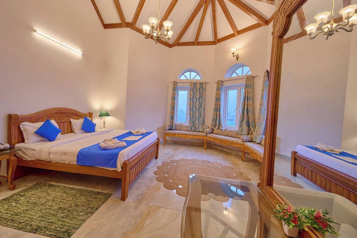 Un dormitorio con una cama de madera, un banco, una mesa de vidrio y un espejo grande.