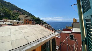 Eine Küstenstadt mit terrakottafarbenen Dächern, blauem Himmel und dem Meer im Hintergrund.