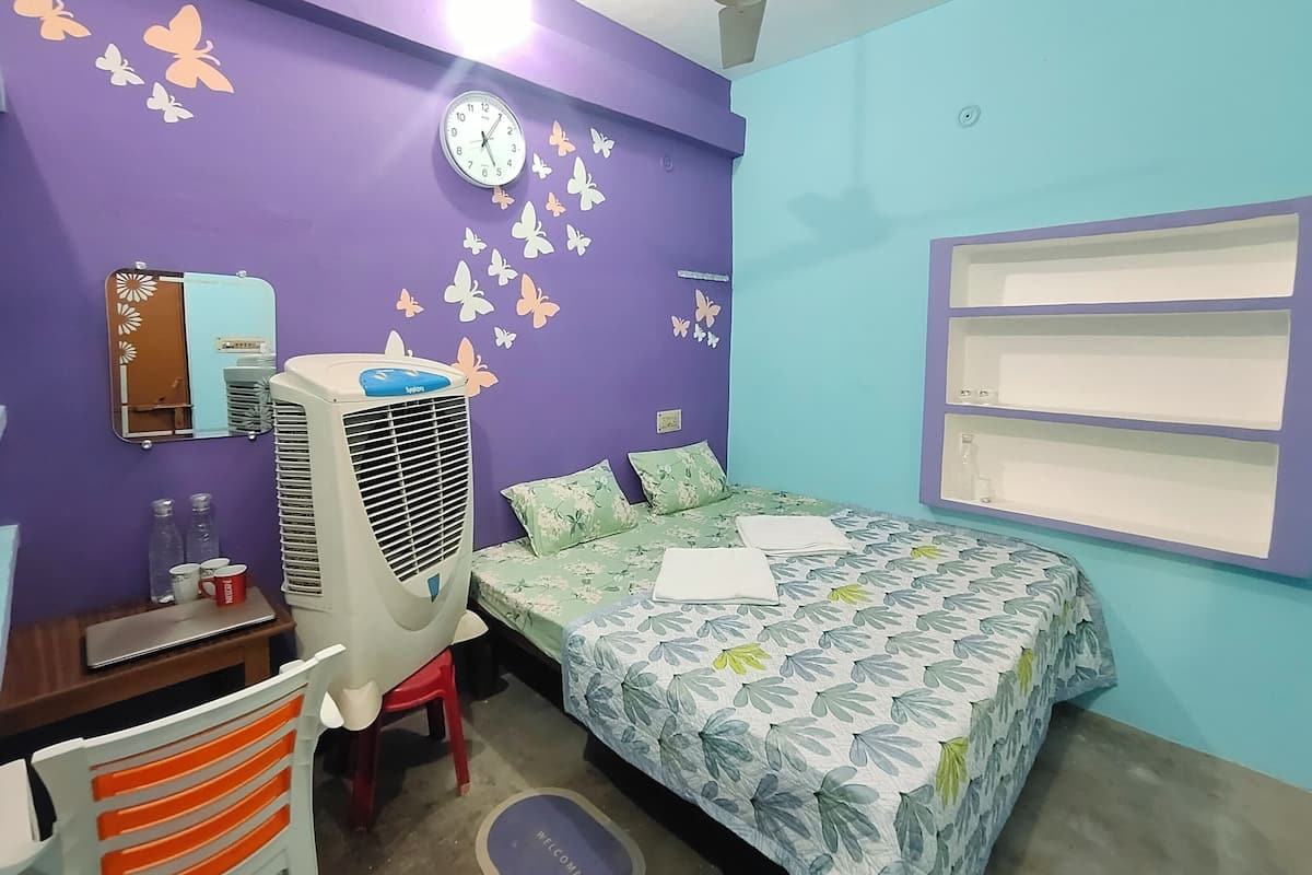 Ein Schlafzimmer mit Bett, Schreibtisch, Stuhl, Heizung, Spiegel und Wandstickern mit Schmetterlingsmotiv.