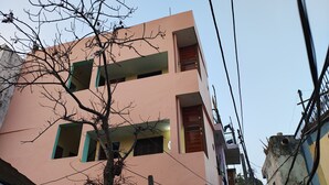 A multi-story building with balconies and a tree in front. - Sneh Homestay (Faizabad)