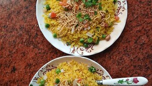Two plates of yellow rice with vegetables and peanuts, served on white plates with floral designs. - Sneh Homestay (Faizabad)