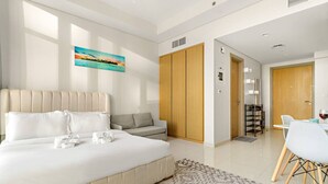 A modern hotel room with a large bed, a sofa, a dining area, and a wardrobe. - FIRST CLASS | Studio | Chic City Escape (Dubai)