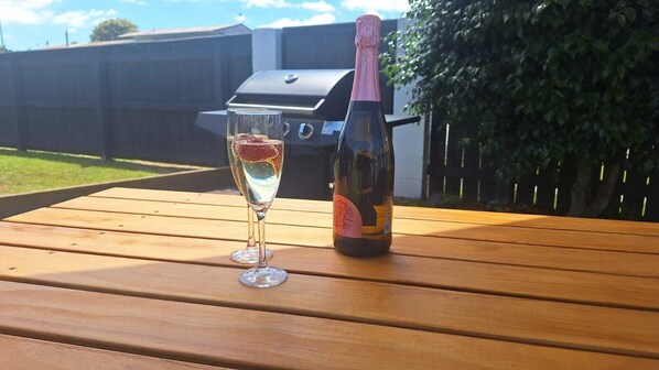 Een fles champagne en een glas op een houten tafel buiten.