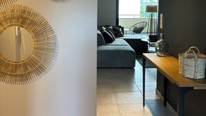 A modern living room with a grey sofa, a wooden side table with a basket, and three wall-mounted circular mirrors.