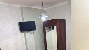 A bedroom with a bed, a wardrobe, a dresser, and a television mounted on the wall. - La Fonte B&B (Baranello)