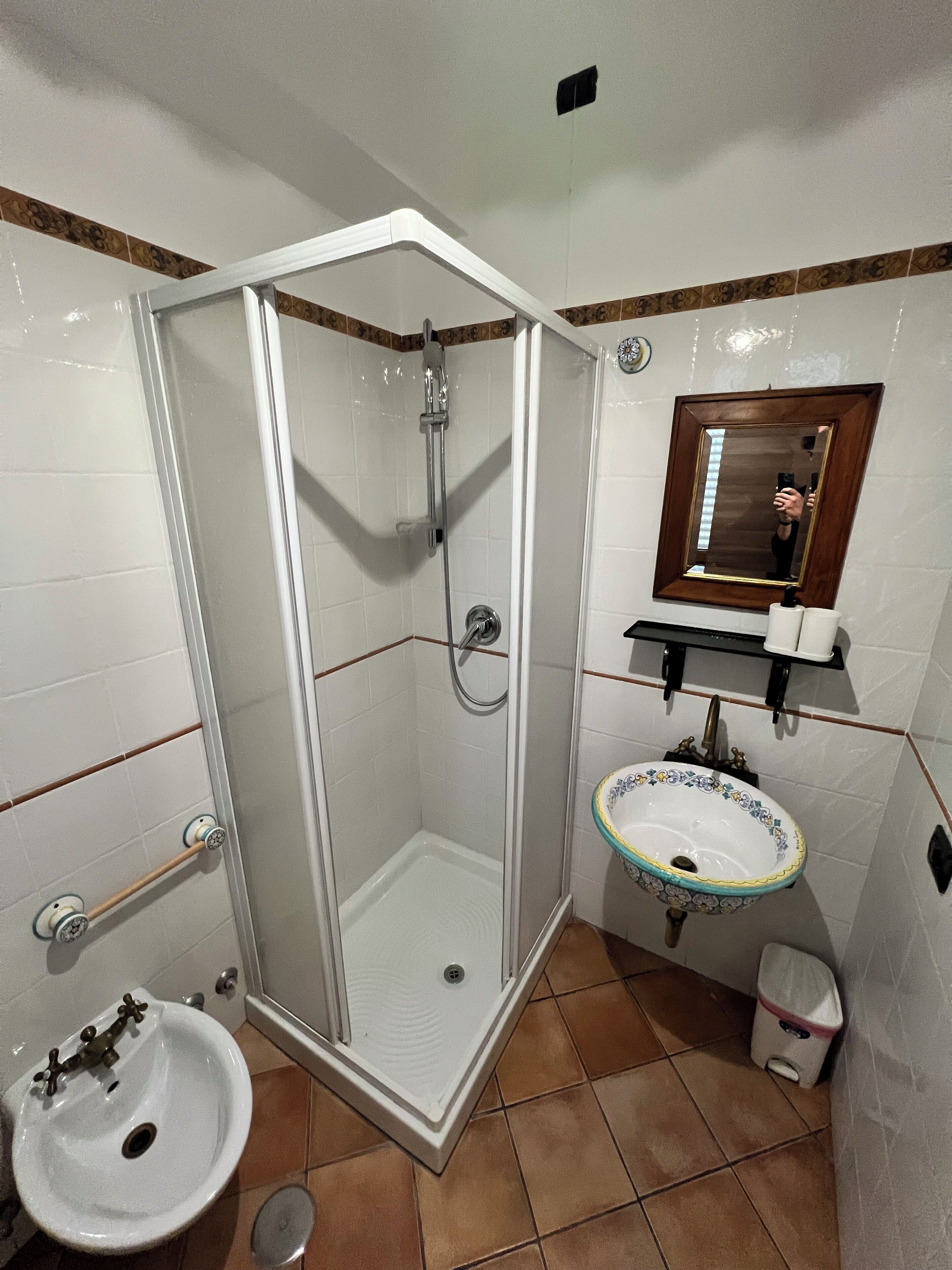 A bathroom with a glass-enclosed shower, a pedestal sink with a decorative basin, and a mirror above the sink.
