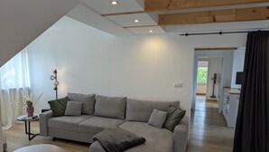 A modern living room with a grey sectional sofa, a small round coffee table, and a tall floor lamp. - Schweigen-Rechtenbach - modern vacation apartment "Martina" ideal for four people (Schweigen-Rechtenbach)