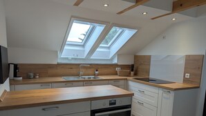 A modern kitchen with a skylight, a built-in oven, and a coffee maker. - Schweigen-Rechtenbach - modern vacation apartment "Martina" ideal for four people (Schweigen-Rechtenbach)