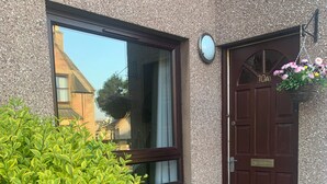 A house with a brown door, a window with a white curtain, and a small step leading to the entrance. - Newly refurbished ground floor flat within easy walking distance of town centre. (Inverness)