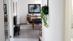 A hallway leading to a dining area with a table and chairs, a television, and a hanging plant. - Benvenuti 30026 Apartment in Somo (Somo)
