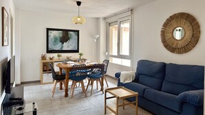 A modern living room with a blue sofa, a dining table with chairs, a TV, and a large mirror on the wall. - Benvenuti 30026 Apartment in Somo (Somo)