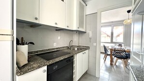 A modern kitchen with white cabinets, a granite countertop, and a dishwasher. - Benvenuti 30026 Apartment in Somo (Somo)