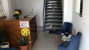 Uma área de recepção com uma mesa de madeira, um sofá azul e uma escada.