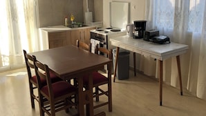 Uma cozinha compacta com armários de madeira, uma mesa de jantar com cadeiras, um fogão pequeno e uma cafeteira.
