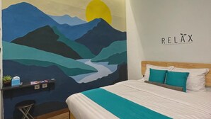 Un dormitorio con cama, un escritorio con silla, un mural en la pared y un letrero que dice 'RELAX'.