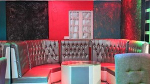 A corner seating area with a tufted leather sofa, a glass coffee table, and a patterned floor. - old station lounge (Naivasha)