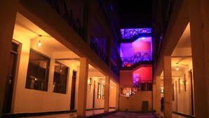 A hotel corridor with multiple doors, a staircase, and a ceiling with purple lighting. - old station lounge (Naivasha)