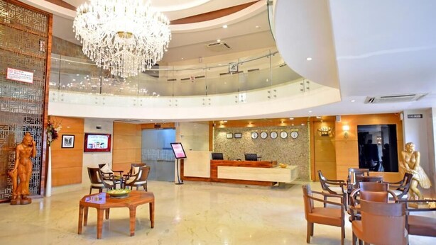 Vestíbulo de hotel con mostrador de recepción, zona de estar y candelabro.