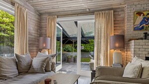 A modern living room with a sofa, a coffee table, and a lamp. There is a sliding glass door leading to an outdoor area.