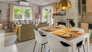 A modern living room with a sofa, dining table, and fireplace.