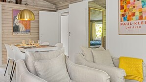A modern interior with a dining area, a sofa with a yellow throw, and a colorful abstract painting.