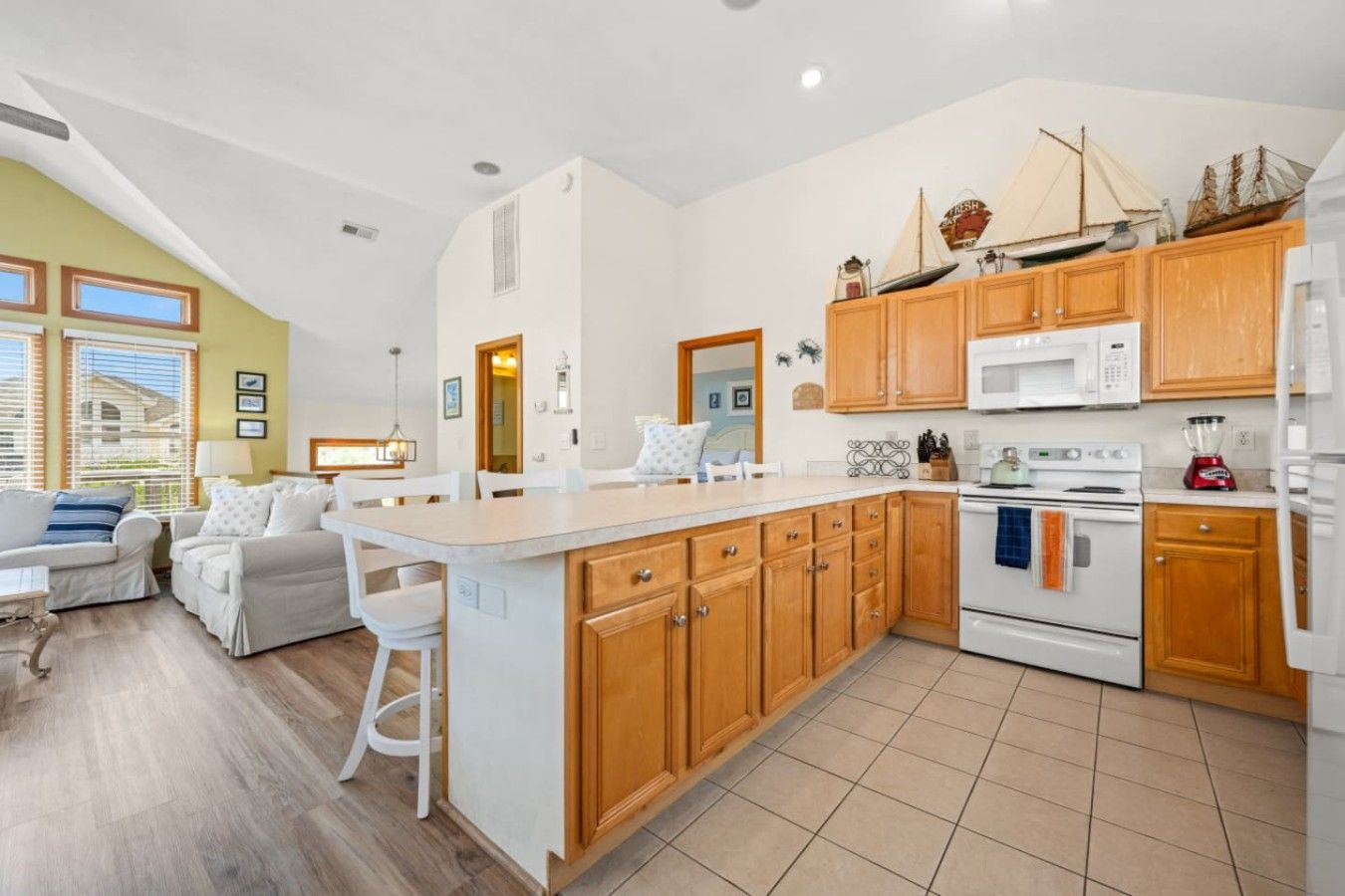 A modern kitchen with wooden cabinets, a central island, and a dining area with a sofa and chairs.
