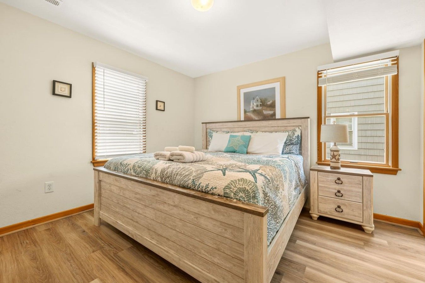 A bedroom with a wooden bed, bedside tables, and a window with blinds.