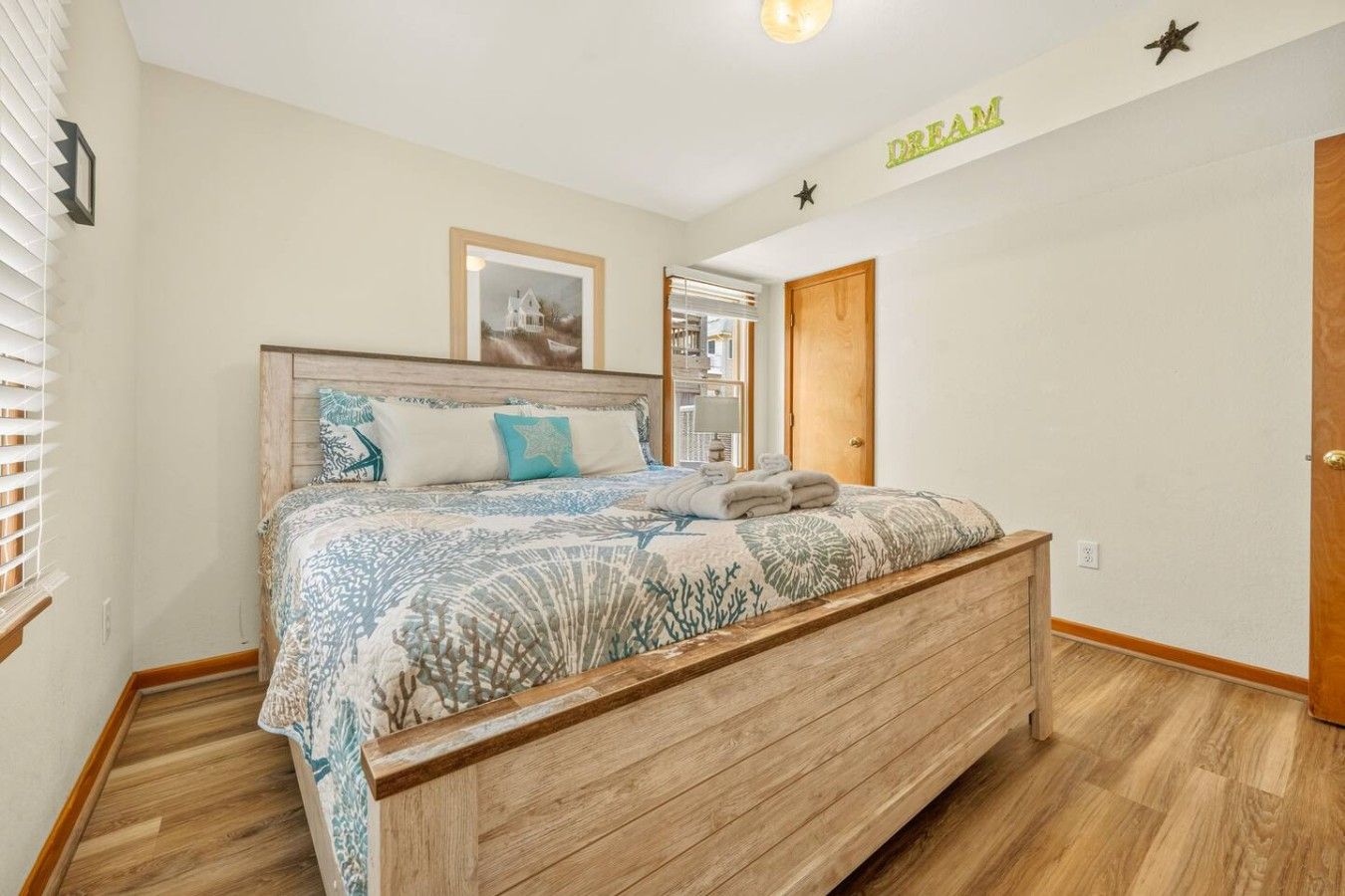 Un dormitorio con cama, cabecera de madera, un cuadro en la pared y una puerta decorada con una estrella.